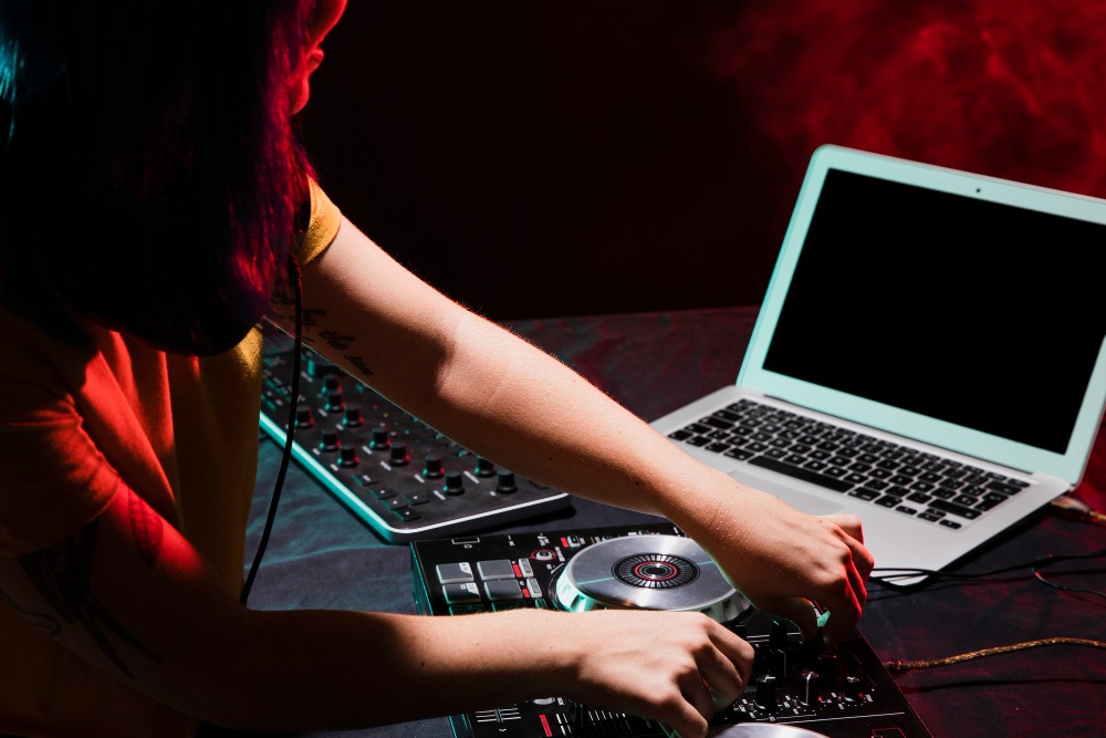 DJ at booth with laptop and controller — one-laptop setup for visuals and DMX