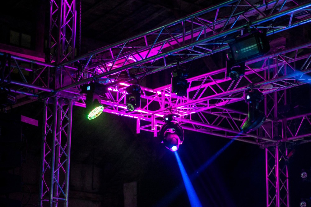 DMX moving head fixtures on a truss lit in magenta at a live event