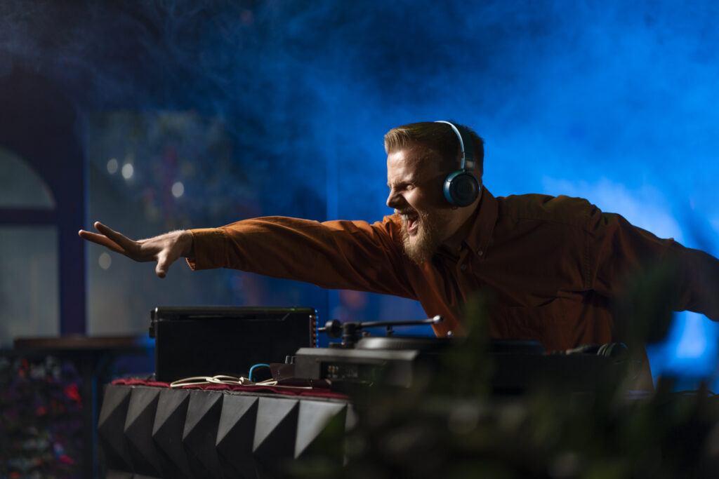 Solo DJ behind the booth with LED wall backdrop and DMX moving heads reacting to music