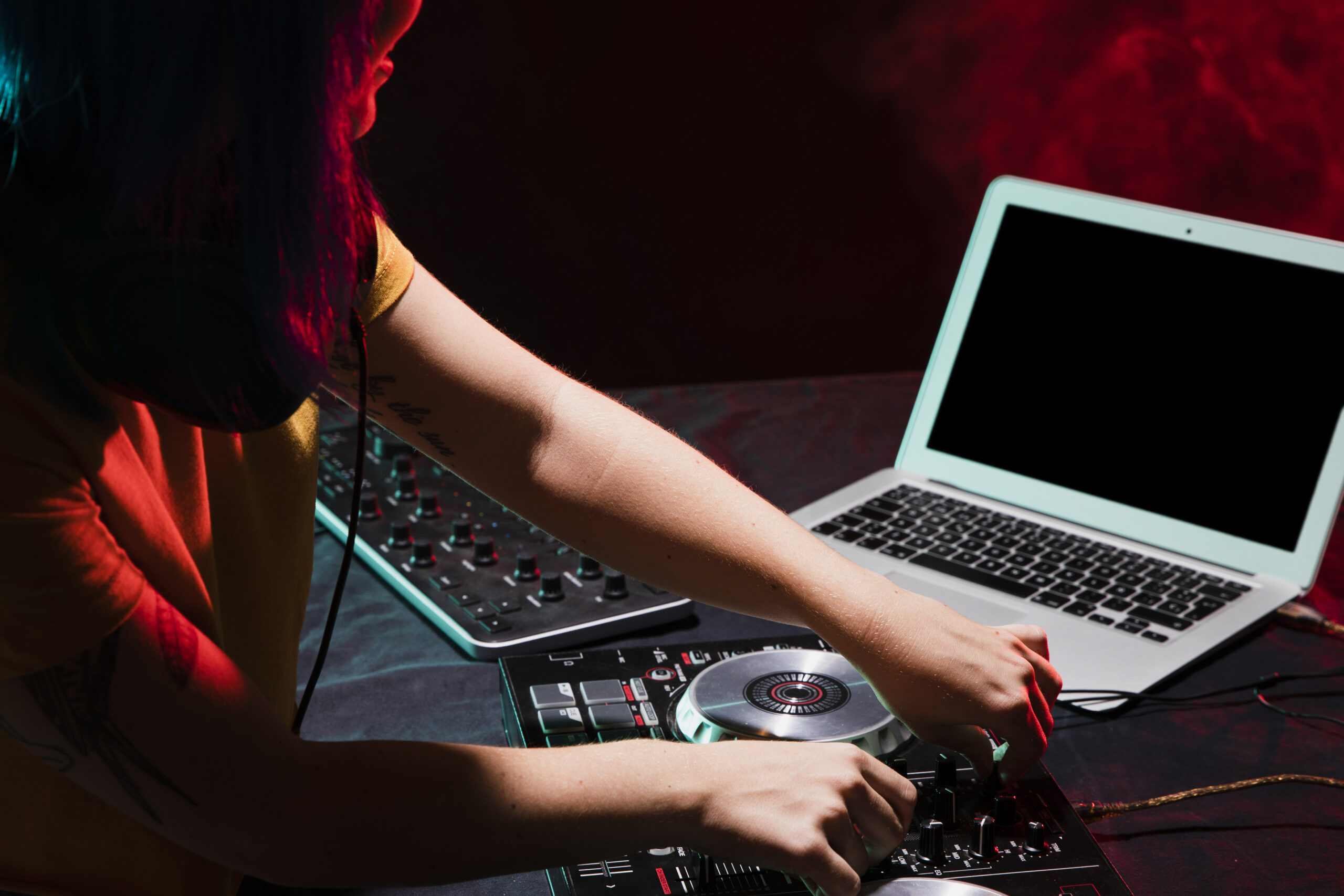 High angle view of a DJ mixing with lights and LED wall running from one laptop